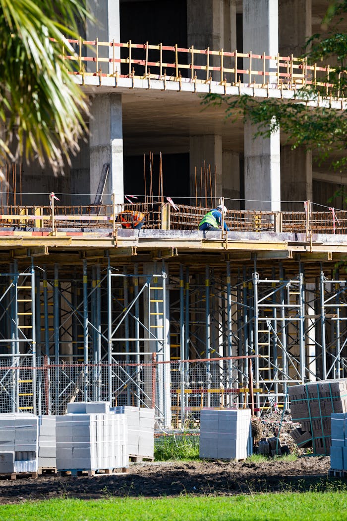 Construction workers on site with scaffolding and materials in sunlight.